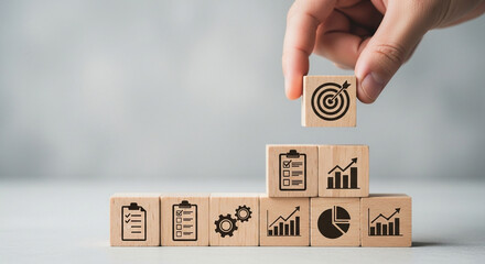 Person placing a target icon block on a stack of blocks with business icons