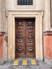 Historic Wooden Church Door with Ornate Carvings, Italy. Captured in an Italian city, the door evokes classical European religious architecture and craftsmanship.