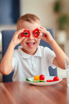 Creative boy playing with vegetables while eating