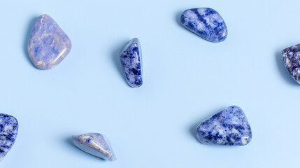 Polished sodalite gemstones arranged on a pastel blue background with soft lighting