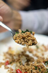Use spoon pick up minced pork with basil to eating. Selective focus