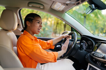 Pregnant black woman driving car and honking horn with expressive gesture, emotional african...