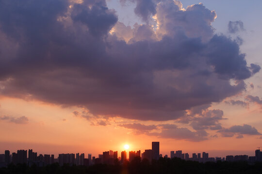 Breathtaking summer evening sunset with dramatic clouds and skyline silhouette, captured at 7 pm in July, showcasing nature's beauty over a vibrant urban landscape. - Powered by Adobe