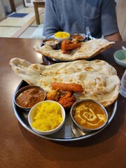 A vibrant, flavorful Indian Thali platter showcases diverse curries, naan bread and rice dishes.