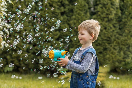Child playing with bubble gun outdoors.