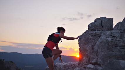 Determined female hiker scales rocky peak at sunset, showcasing endurance and adventure in stunning...