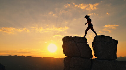 Determined runner conquers rocky peak at sunset, symbolizing endurance and triumph. Golden sky and...