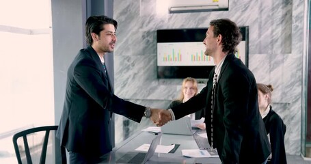 Two businessmen shaking hands after successful presentation, closing corporate deal with trust and agreement, businesswoman in background smiling, team acknowledging partnership progress