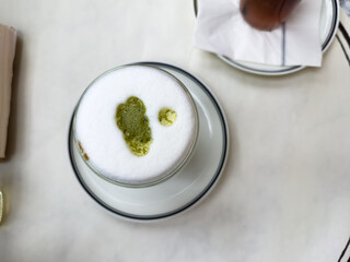 Transparent glass of matcha green tea in cafe on white table. High quality photo