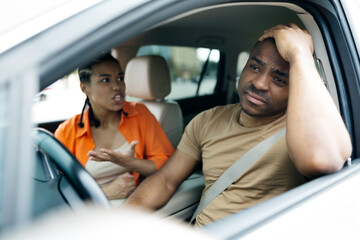 Tense moment inside the car as young African American couple has an argument during their road trip. Woman expresses frustration while man looks distressed, closeup