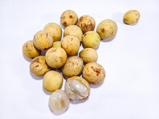 A small pile of duku fruit, with one peeled to reveal its translucent flesh, set against a white background. Related to tropical food and agriculture, healthy eating initiatives, or the unique produce