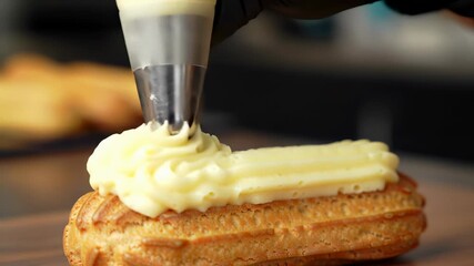Close-up of Piping Cream onto a Freshly Baked Eclair in a Pastry Kitchen