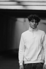 young boy wearing a white blouse and black jeans standing on concrete wall. urban street style