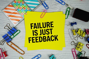 Failure Is Just Feedback text on stick note with stationery on concrete background