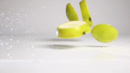 Crisp Green Apple Slices Splashing Down in Slow Motion on a White Surface - Powered by Adobe