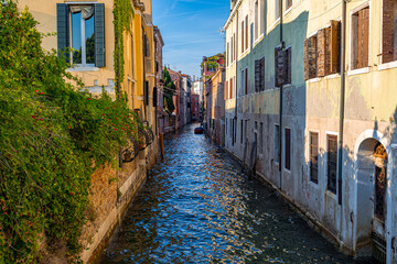 A photo of a narrow canal with a few buildings and a few trees