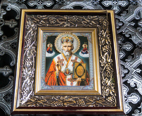 Religious icon of Saint Nicholas in ornate frame displayed on decorative background