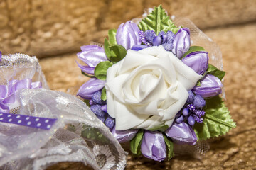 Elegant floral corsage with white rose and purple blooms for special occasions in a warm indoor setting