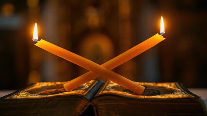 Crossed candles on open book, symbolizing religious faith or prayer
