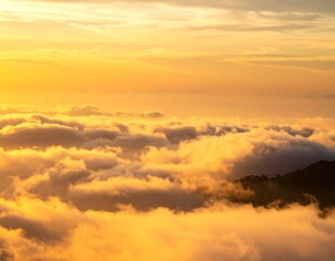 Fototapeta premium Golden light shines on a sea of clouds, partially obscuring a mountain peak at sunrise or sunset.
