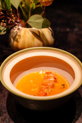 Plated marron tail served in a vibrant orange broth, presented in an elegant ceramic bowl. 