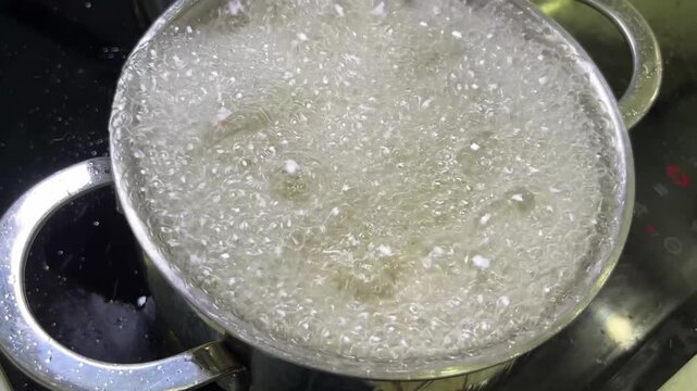 Hand lowering breaded chicken into hot oil, beginning the frying process with bubbling oil action