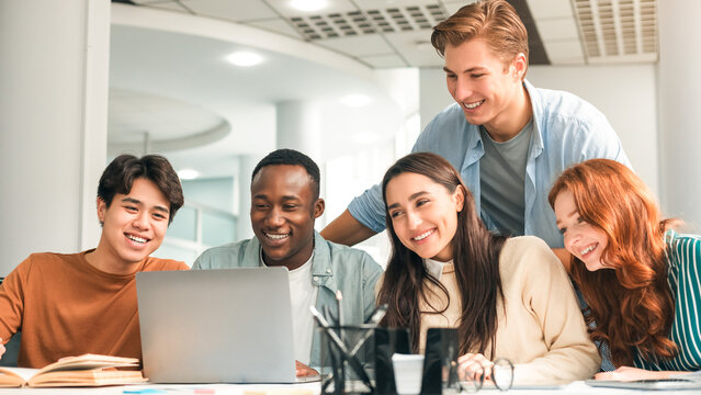 Collaboration Concept. Portrait of smiling multiethnic people sitting at table in modern workspace using laptop, watching tutorial or webinar, happy millennials discussing group project or startup - Powered by Adobe