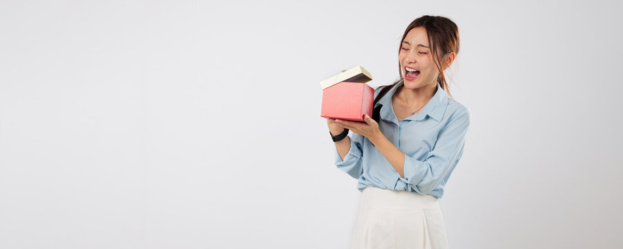 Gift reveal begins as happy woman opens surprise box during celebration, then finds a second little gift adding extra joy to the moment. isolated studio white background