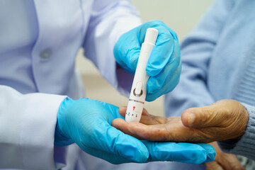 Asian doctor using digital glucose meter for check sample blood sugar level to treatment diabetes.