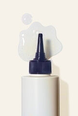 Clear transparent scalp peeling aha bha gel swatch and white tube with black cape on light grey background