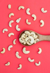 Top View of Cashew Nuts in a Wooden Spoon Isolated on Red Background with Copy Space in Vertical Orientation, Healthy Eating Dry Fruit