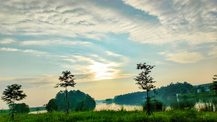 A Stunning Morning Panorama on the Shore of a Serene Lake welcoming the sunrise, with Lush Green Nature and Breathtaking Views that Induce Serenity and Wonder