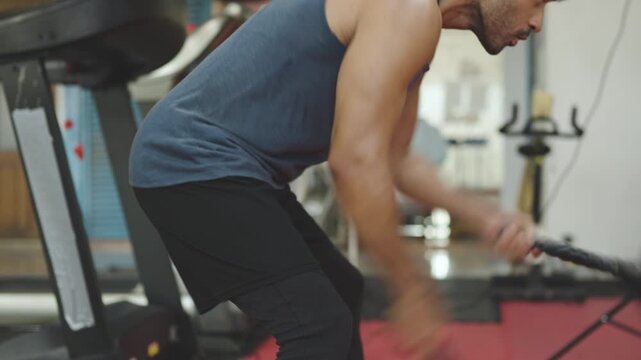 Sport and wellness concept. Man doing cable rope tricep pushdowns during gym workout. Male athlete exercising for arm strength and muscle definition. Indoor fitness training for upper body power.