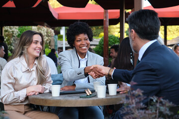 Businesspeople shaking hands during a meeting at an outdoor cafe, closing a deal and celebrating success