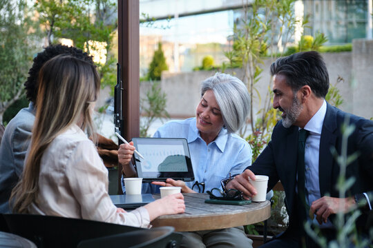 Businesspeople having a meeting discussing a chart on tablet at outdoor cafe