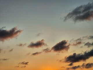 Colorful sunset sky with scattered dark clouds and warm orange evening glow