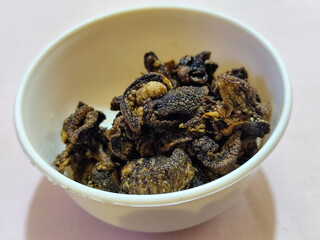 Flourless snail chips have a savory, delicious and crunchy taste. Presented with a white bowl with a natural blur background.