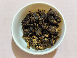 Flourless snail chips have a savory, delicious and crunchy taste. Presented with a white bowl with a natural blur background.