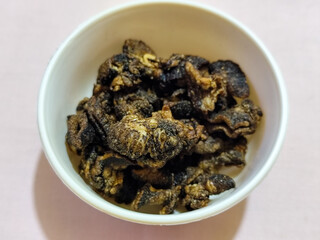 Flourless snail chips have a savory, delicious and crunchy taste. Presented with a white bowl with a natural blur background.