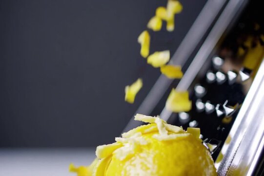 Cinematic macro of lemon zest being grated, particles flying in slow motion