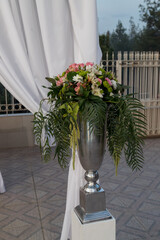 Elegant floral arrangement displayed in a silver vase enhances the ambiance of an outdoor celebration at dusk