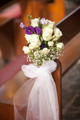 Elegant floral arrangement adorning a pew in a charming church during a heartfelt wedding ceremony