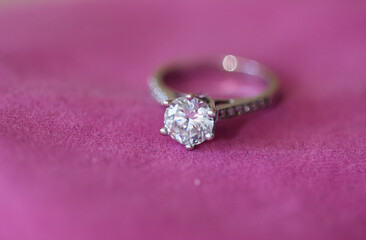 Sparkling diamond ring showcased on luxurious pink velvet, evoking elegance and romance in soft lighting