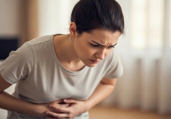 Distressed young woman feeling unwell with severe abdominal pain, holding her stomach due to menstrual cramps, indigestion, or illness. road541