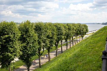 Fototapeta premium View from the top of the hill slope to the embankment with trees in a row