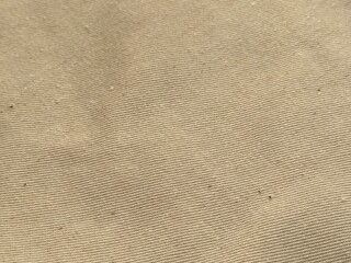 Close-up of light brown shirt fabric texture. Soft, detailed beige cloth surface, natural fibers, perfect for fashion, textile, apparel, background, design, and fabric-related projects