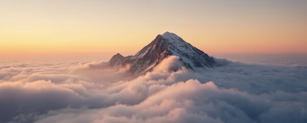 Mountain peak rises through clouds at sunrise with snow-capped peaks reaching warm sunset hues. Gradient sky of orange, pink hues with gentle glow on mountain. Valley green foreground with vibrant