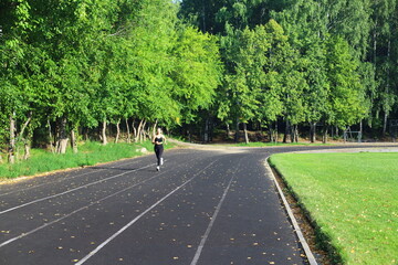 Fototapeta premium Adult European Woman in Black Running in Open Stadium.