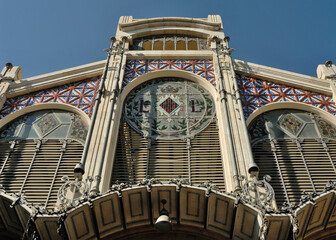 Colón Market facade with colorful Valencian tiles and stained glass windows showing the LL letters