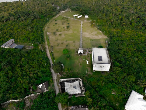Aerial view of buildings nestled among dense green trees, a pathway leading through vibrant foliage, Bori, Rivers, Nigeria.